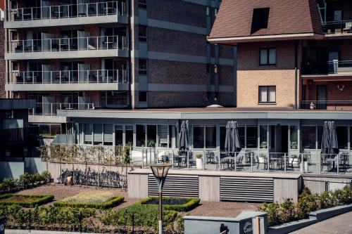 ein Gebäude mit Tischen und Sonnenschirmen davor in der Unterkunft Casino Hotel in Koksijde