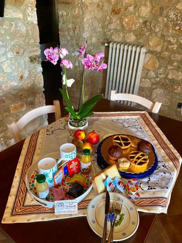 a table with breakfast foods and flowers on it at B&B Fontanelle in Alviano