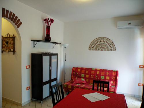 a living room with a red couch and a table at Appartamento residence casa vacanza in Santa Teresa Gallura