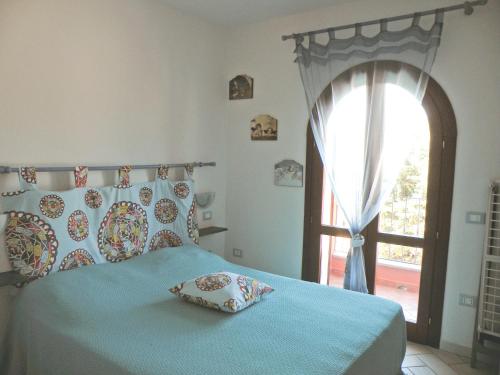 a bedroom with a bed with a blue blanket and a window at Appartamento residence casa vacanza in Santa Teresa Gallura