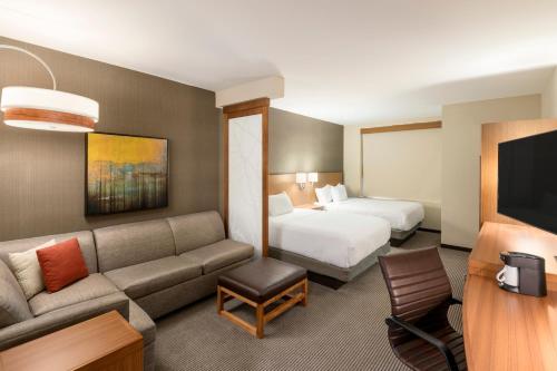 a hotel room with a couch and a bed at Hyatt Place Greenville Downtown in Greenville