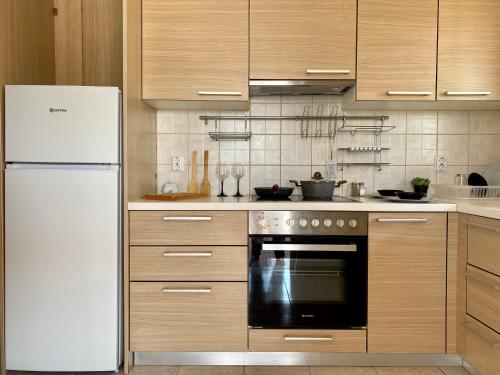 a kitchen with a white refrigerator and wooden cabinets at Peaceful Apartment, in the nature, with yard "3" in Zipárion