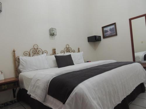 a bedroom with a large bed with white and black sheets at Hotel Concierge Plaza Colima in Colima