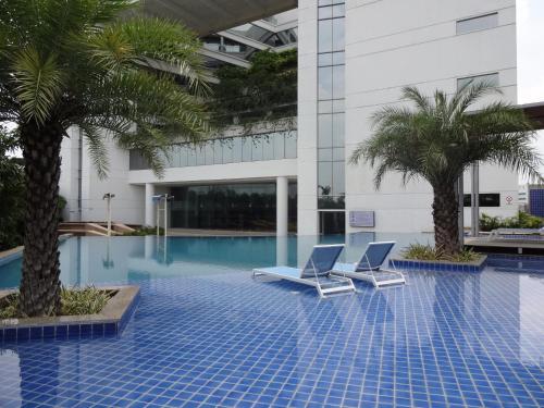 a pool with two chairs and palm trees in a building at Avasa Hotel in Hyderabad