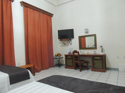 a bedroom with a bed and a desk with a mirror at Hotel Concierge Plaza Colima in Colima