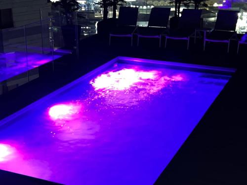 a swimming pool with purple lights in a room at The Royal Penthouse in Bat Yam