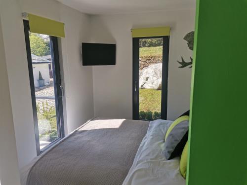 a bedroom with a bed and a tv and windows at The Wee Den in Balfron