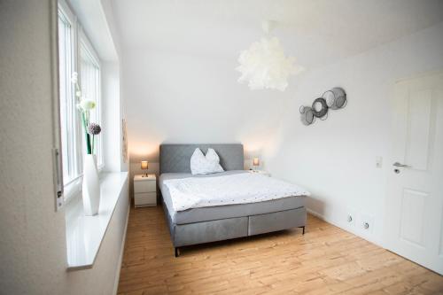 um quarto com uma cama num quarto branco em Haus Nordseeliebe mit Außensauna, Outdoor Dusche und Wallbox em Dornum