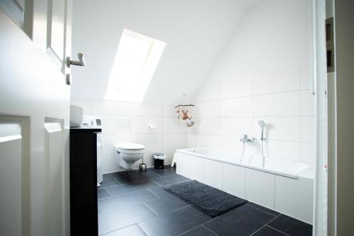 a white bathroom with a tub and a toilet at Haus Nordseeliebe mit Außensauna, Outdoor Dusche und Wallbox in Dornum