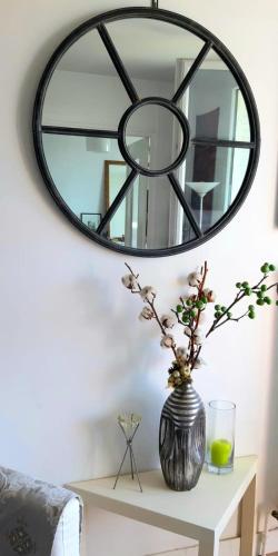 un miroir sur un mur au-dessus d'une table avec un vase dans l'établissement Charming bright T2 balcony parking telework, à Annecy