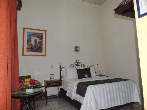 a bedroom with a bed and a table with flowers at Hotel Concierge Plaza Colima in Colima