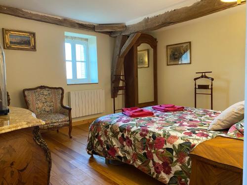 ein Schlafzimmer mit einem Bett und einem Stuhl in der Unterkunft Le brûlon in Bourg-le-Comte