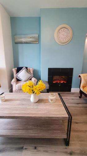 a living room with a table with yellow flowers on it at Beulah Guest House in Portrush