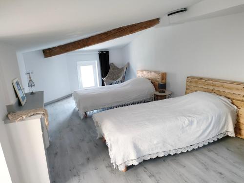 twee bedden in een kamer met witte muren en houten vloeren bij Gîte chaleureux "Le Figuier" - Val-du-Faby in Fa