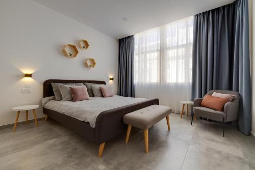 ein Schlafzimmer mit einem großen Bett und einem Stuhl in der Unterkunft Perfect Location, Modern 2BR Apartment in Sliema