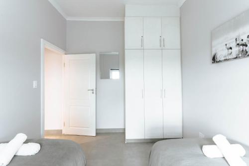 two beds in a white room with white cabinets at Kingswood Manor No.17 in George