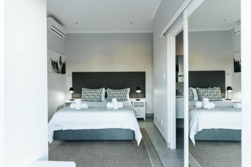 a white bedroom with two beds and a mirror at Kingswood Manor No.17 in George