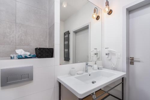 a white bathroom with a sink and a mirror at Apartament Mechelinki in Mechelinki
