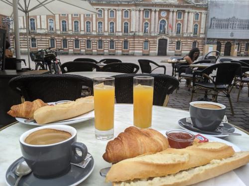 - une table avec des tasses de café, des croissants et du jus d'orange dans l'établissement Etape Urbaine - Toulouse centre - Parking inclus, à Toulouse