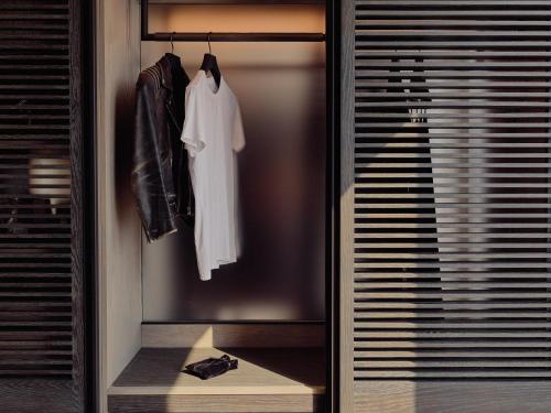 a walk in closet with a white shirt and jacket at Equinox Hotel New York in New York