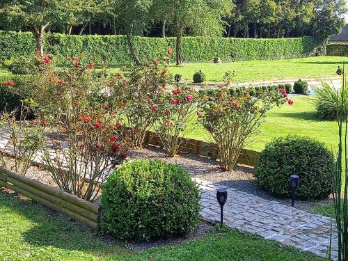 a garden with some bushes and red roses at chambres et gites d'étretat in Étretat