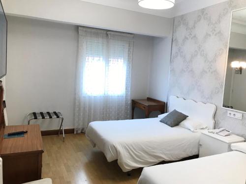 a hotel room with two beds and a window at Hostal La Mexicana in Santander