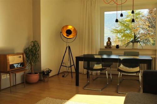 a living room with a table and chairs and a window at La Vista - Apartment mit Traumblick & Garten in Marlengo