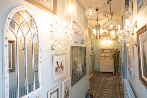 a hallway with chandeliers and paintings on the walls at Vale House in Belvoir