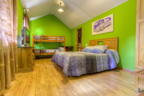 a green bedroom with two beds and a television at Hostal Rural La Tintoreria in Villablino