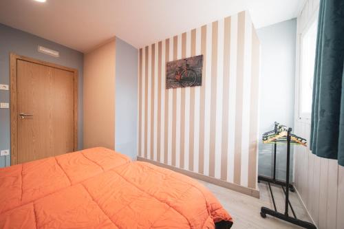 a bedroom with an orange bed and a striped wall at Albergue Barullo - Cubículos - Literas - Habitaciones in Sarria