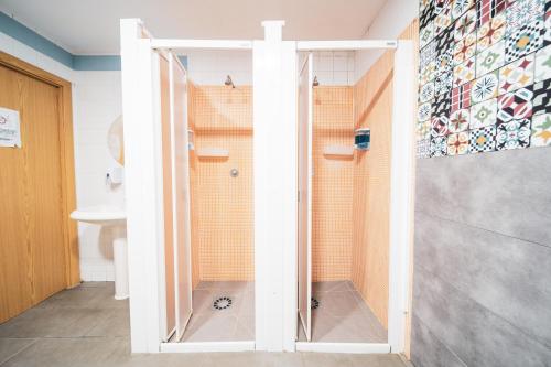 a shower with a glass door in a bathroom at Albergue Barullo - Cubículos - Literas - Habitaciones in Sarria