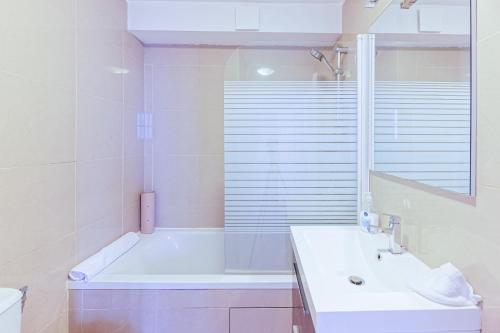 a white bathroom with a tub and a sink at Dogon Reef Biarritz - Plages - Halles - Hypercentre in Biarritz