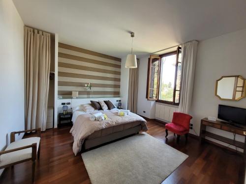 a bedroom with a large bed and a red chair at Villa Lia - Apartment in Villa with private garden and Pool in Florence