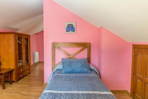 a bedroom with a bed in a pink wall at Hostal Rural La Tintoreria in Villablino