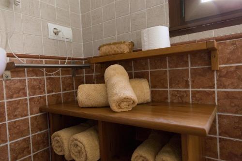 a bathroom with wooden shelves with towels and toilet paper at Hostal Rural La Tintoreria in Villablino
