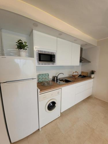 Una cocina con gabinetes blancos, fregadero y lavavajillas. en NAUTILUS VISTAS MAR, NUEVO Centro Salou, en Salou