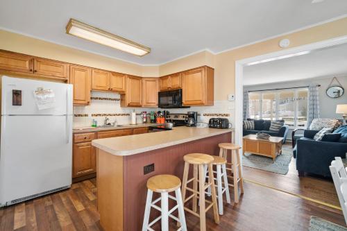a kitchen and living room with a refrigerator and stools at ⭐️The Lucky 7 Beach House⭐️Water view⭐️4 bedroom⭐️ in Brigantine
