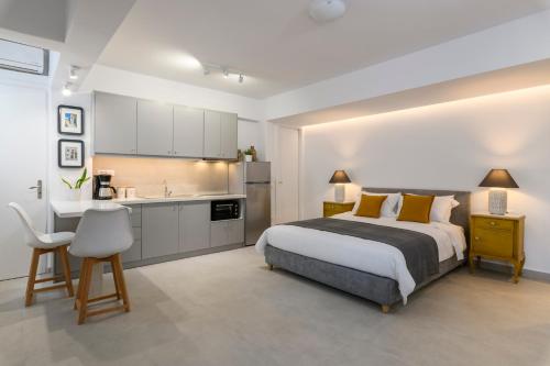 a bedroom with a large bed and a kitchen at Blueisla GREY Studio Town Mykonos in Mýkonos City