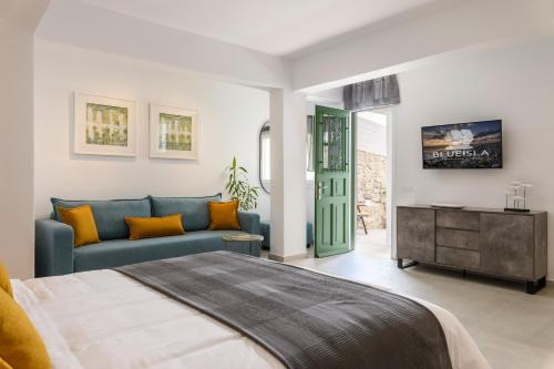 a bedroom with a blue bed and a couch at Blueisla GREY Studio Town Mykonos in Mýkonos City