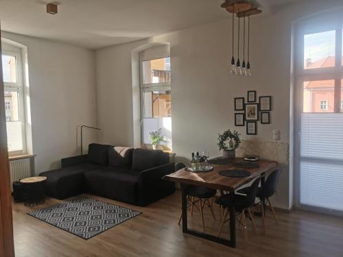 a living room with a black couch and a table at Apartament KurOrt Gaja in Jelenia Góra