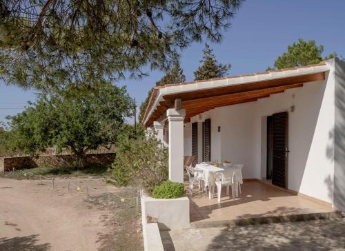 una piccola casa bianca con tavolo e sedie di Viviendas Ferrer - Formentera Break a Playa Migjorn