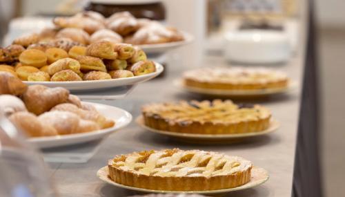 a counter with pies and other pastries on plates at Hotel Morena Riccione Centrale in Riccione