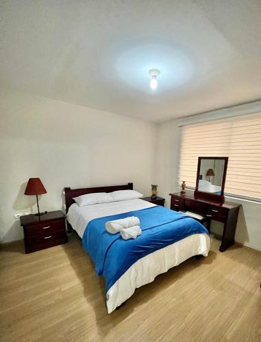 a bedroom with a large bed with a blue blanket at VFC Suites Cuenca - Ecuador in Cuenca