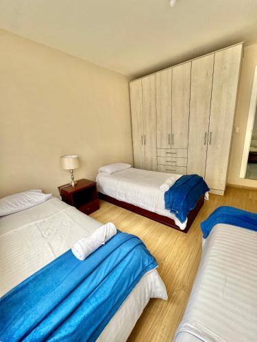 a bedroom with two beds with blue and white sheets at VFC Suites Cuenca - Ecuador in Cuenca