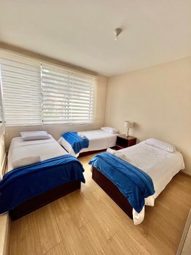 three beds in a bedroom with a window at VFC Suites Cuenca - Ecuador in Cuenca