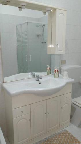a white bathroom with a sink and a mirror at La Dolce Oasi in Triscina