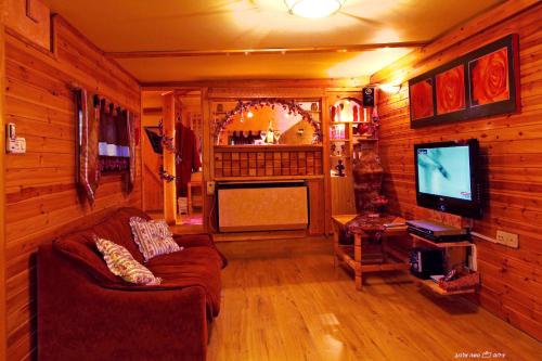 a living room with a couch and a television at Under the Walnut Tree Shade Lodge in Adi