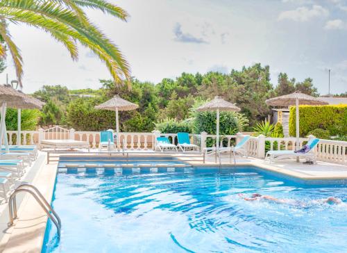 a swimming pool with chairs and umbrellas at Roquetes Rooms - Formentera Break in Es Pujols