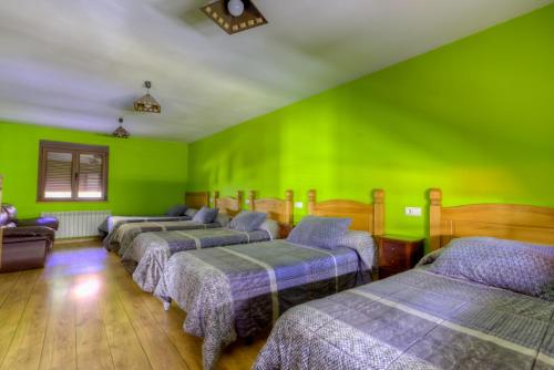 Habitación con 4 camas y paredes verdes. en Hostal Rural La Tintoreria, en Villablino