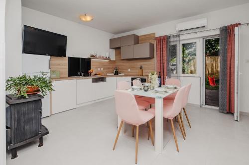 a kitchen with a dining table and pink chairs at Apartman Branko in Zaboric